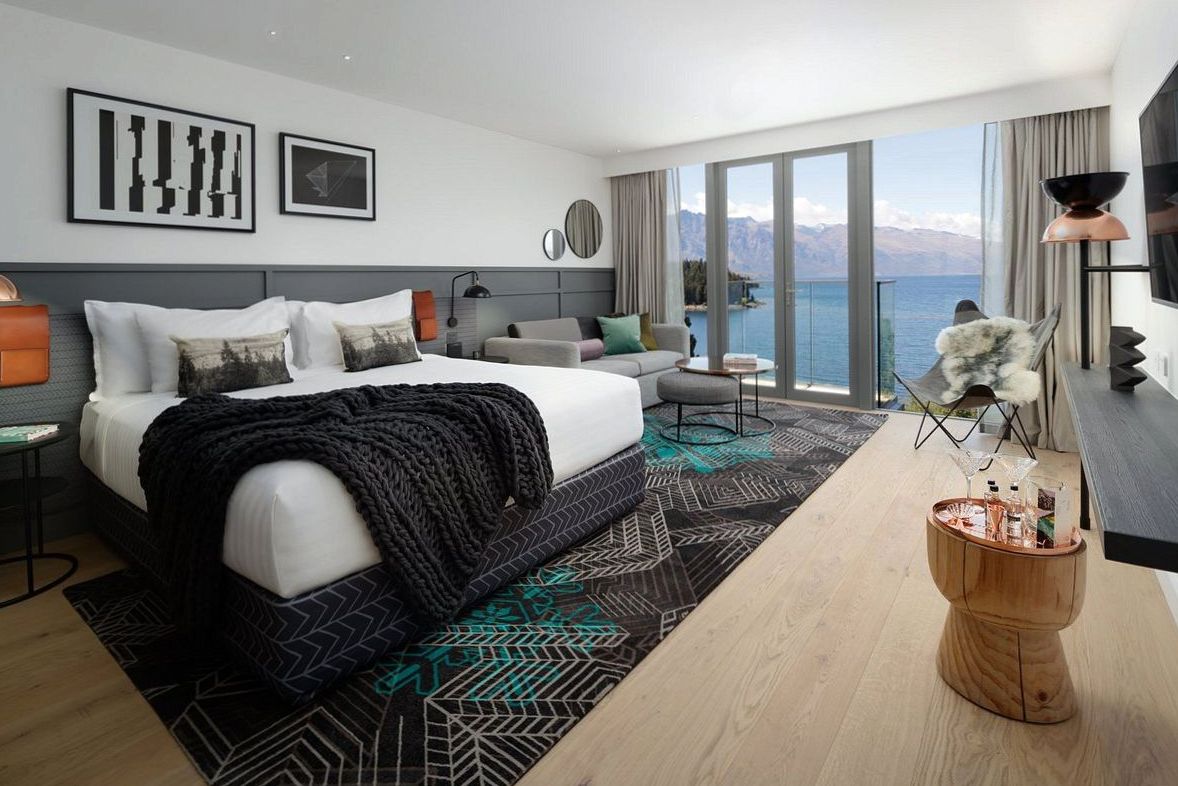 Junior suite with open-plan bedroom and lounge, warm timber tones and lake outlook